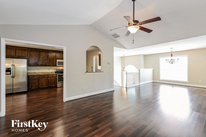 an empty living room and kitchen with a ceiling fan