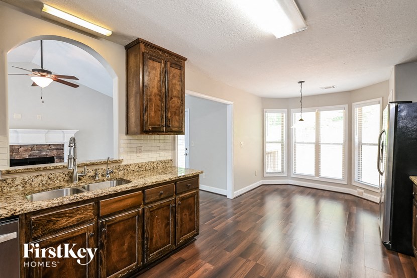 an empty kitchen and living room with wood flooring and a large window