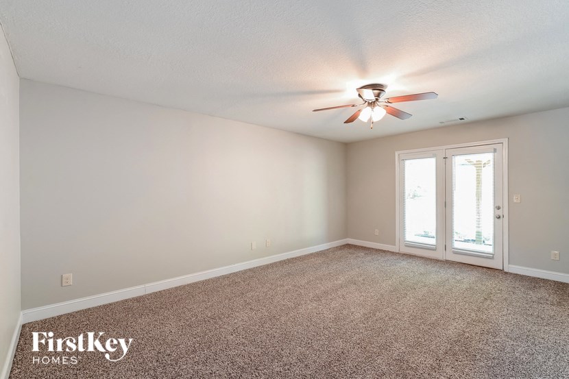 an empty living room with a ceiling fan and a window