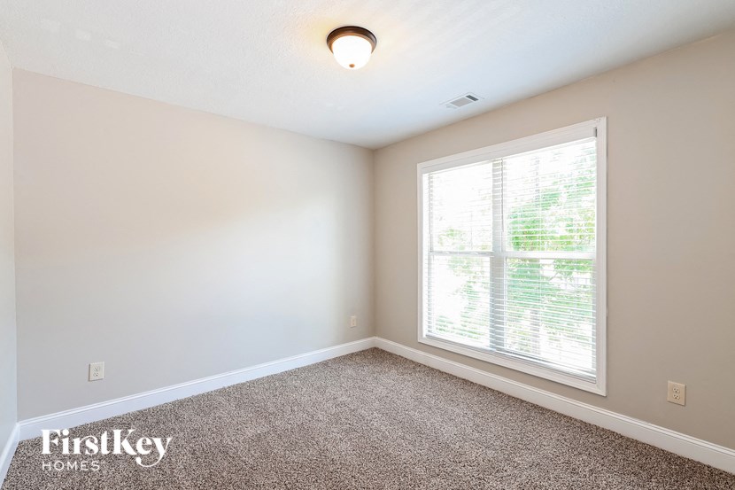 an empty room with a large window and a carpet
