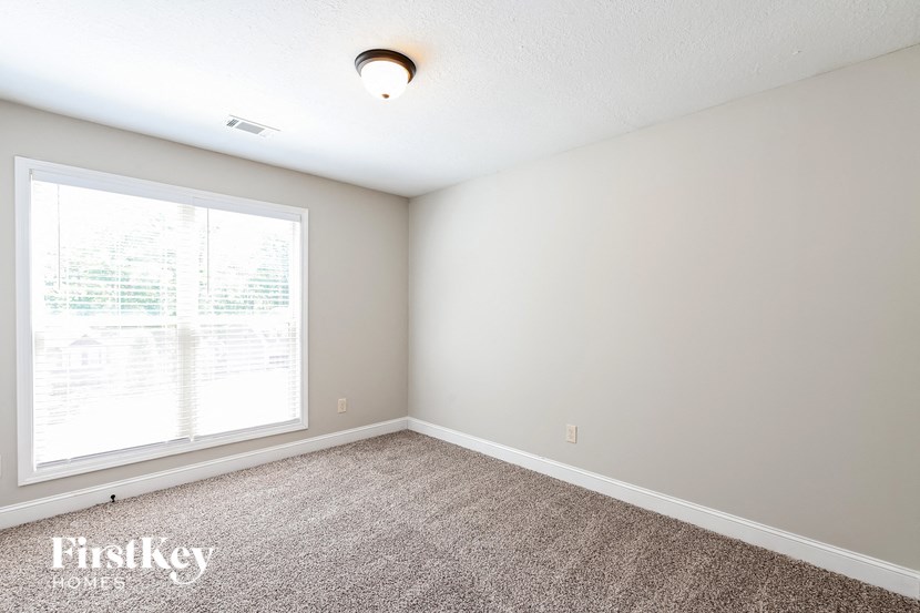 an empty room with a large window and carpeting