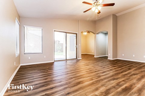 A spacious room with wooden floors and a ceiling fan.