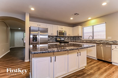 A kitchen with a refrigerator, microwave, and oven.