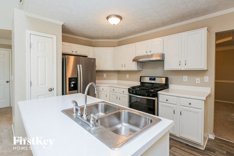 a kitchen with white cabinets and a stainless steel sink