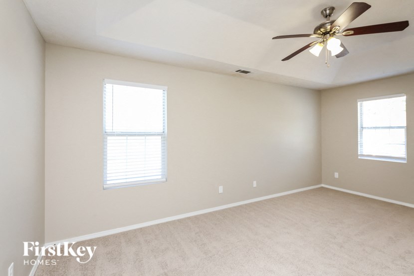 a bedroom with a ceiling fan and two windows