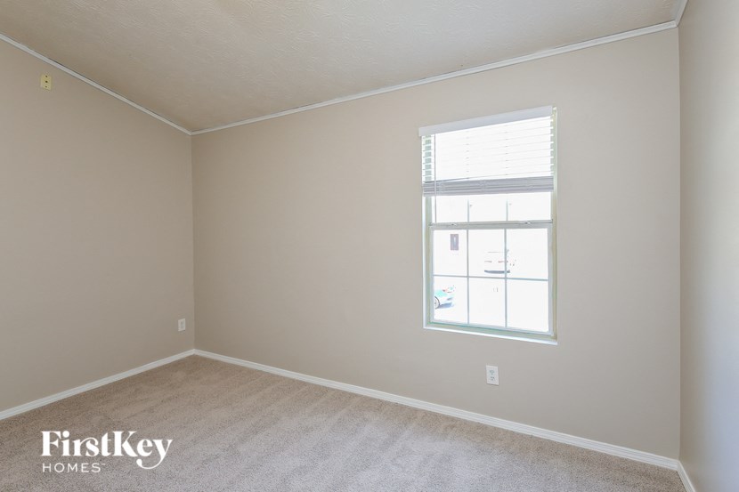 a bedroom with a window and a carpeted floor