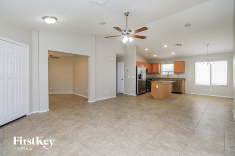 A spacious living room with a ceiling fan and tiled flooring.