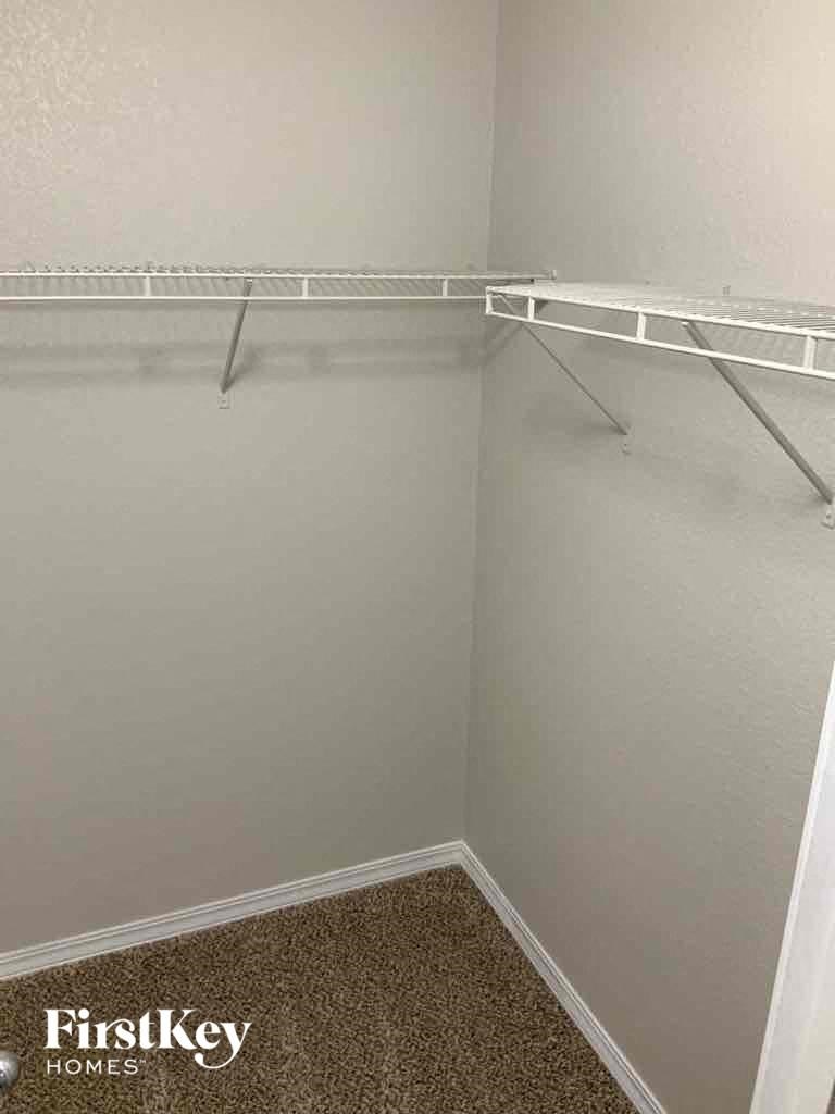a walk in closet with empty shelves in a small room