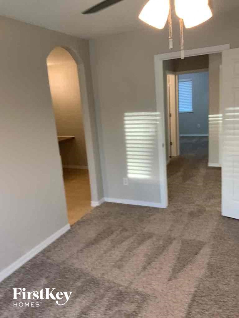 a living room with a carpet and a hallway with a door to a bathroom