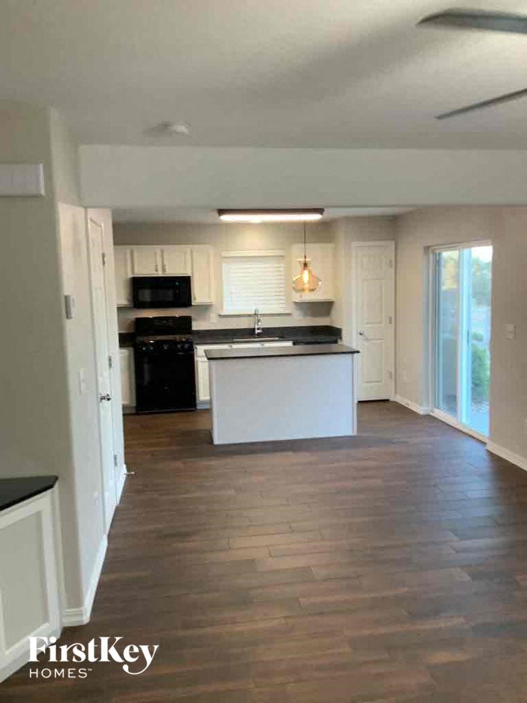 an empty living room and kitchen with wood flooring