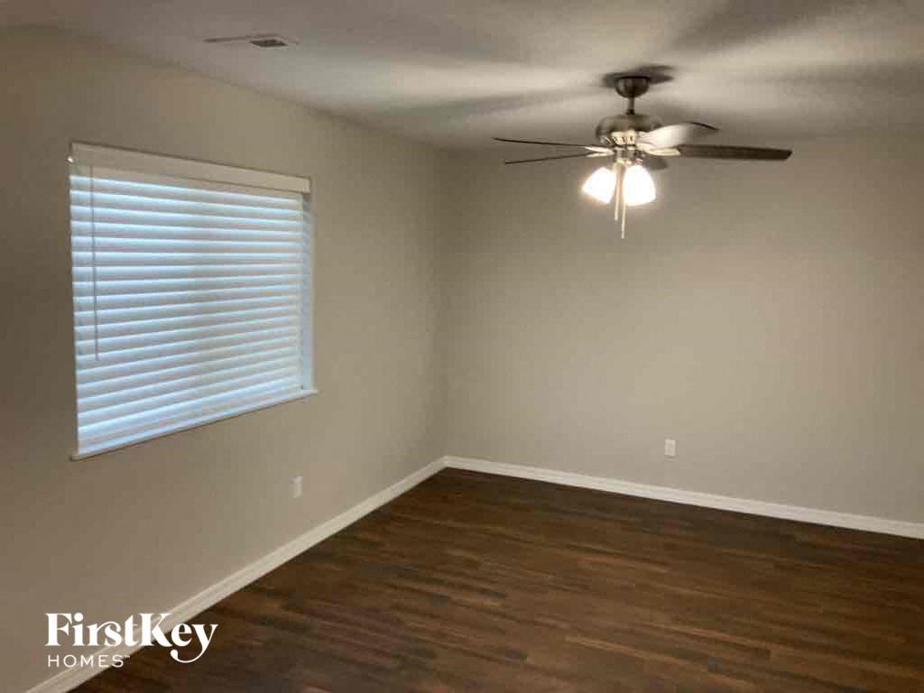 an empty living room with a ceiling fan and a window