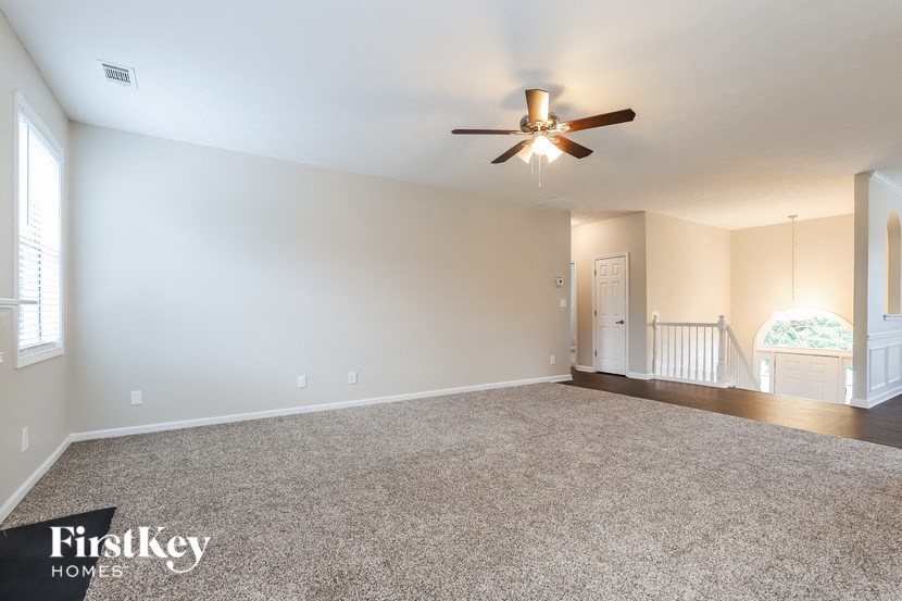 an empty living room with a ceiling fan
