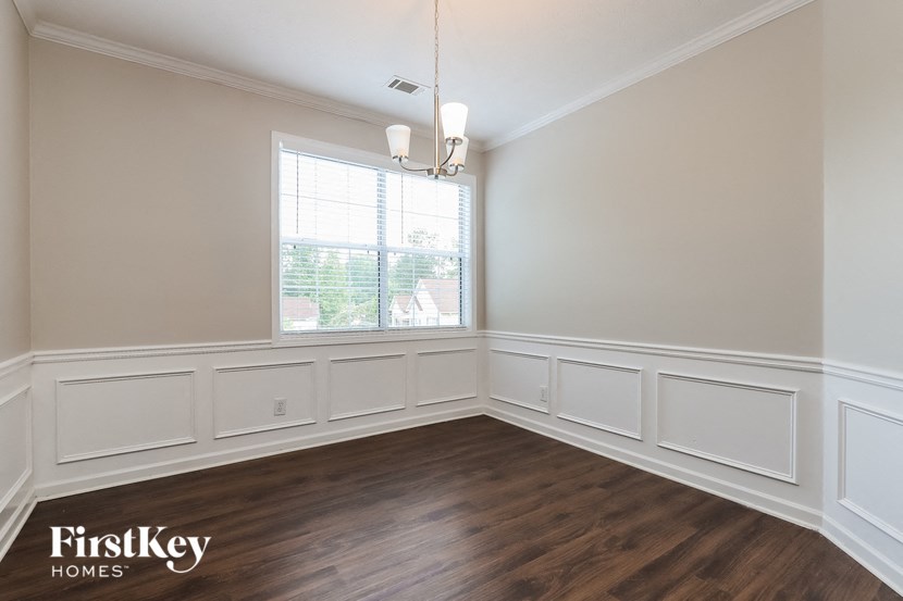 an empty dining room with wood flooring and a window