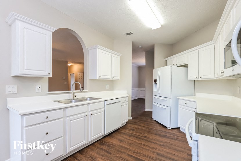 a kitchen with white cabinets and a sink and a refrigerator