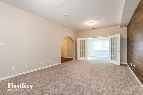 the living room and dining room of a house with carpet and a door