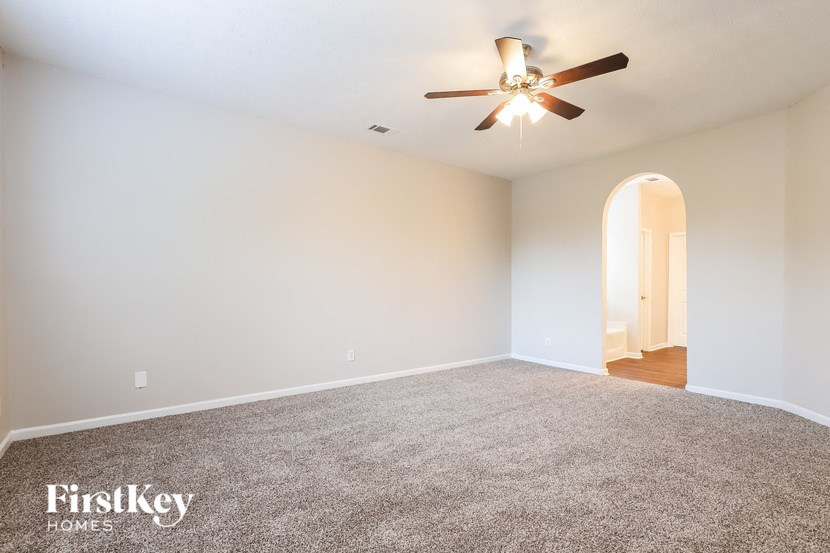 an empty living room with a ceiling fan and carpet