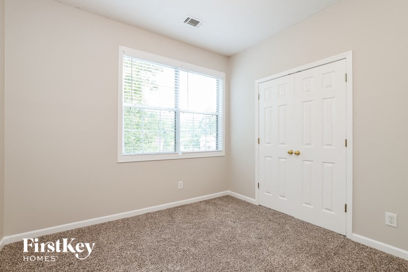 the bedroom of a home with a white door and a window