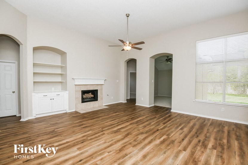 an empty living room with a fireplace and a ceiling fan