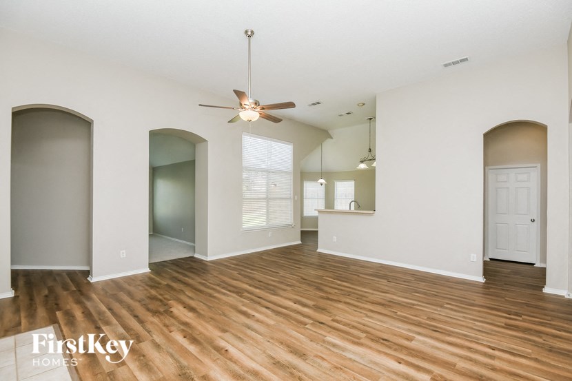 an empty living room with white walls and a ceiling fan