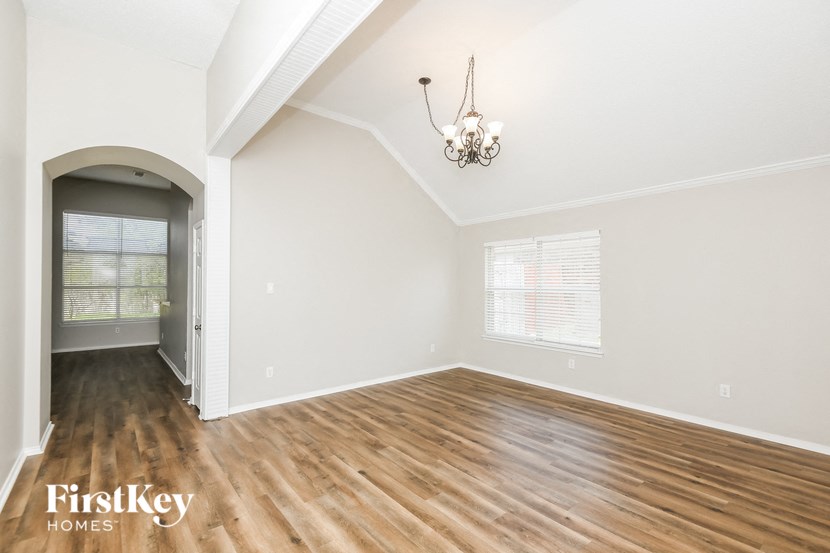 an empty living room with wood flooring and a door to a hallway