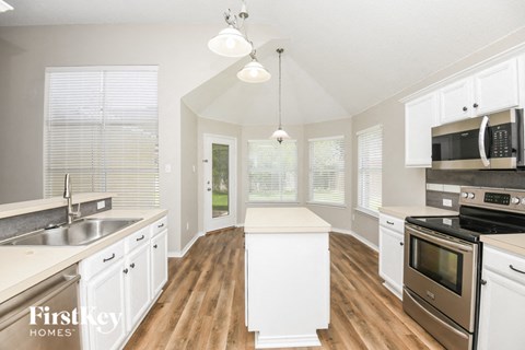 a large kitchen with white cabinets and stainless steel appliances