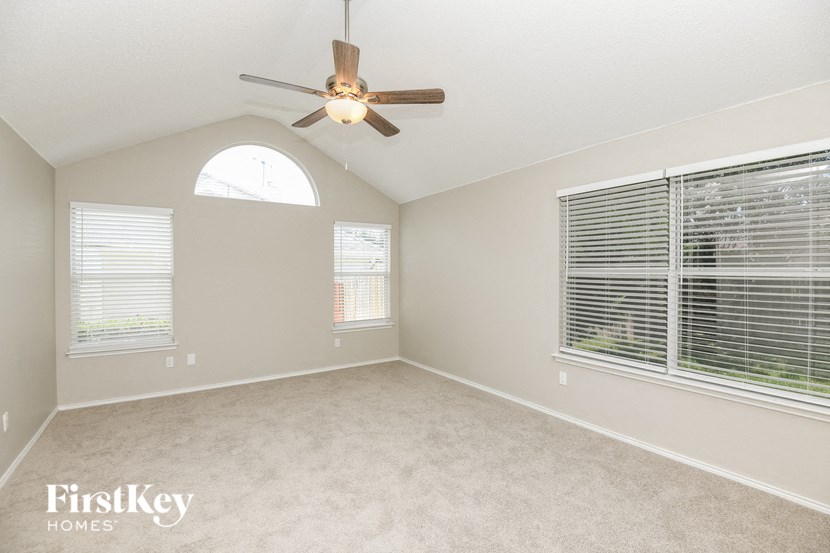 an empty living room with a ceiling fan and a large window