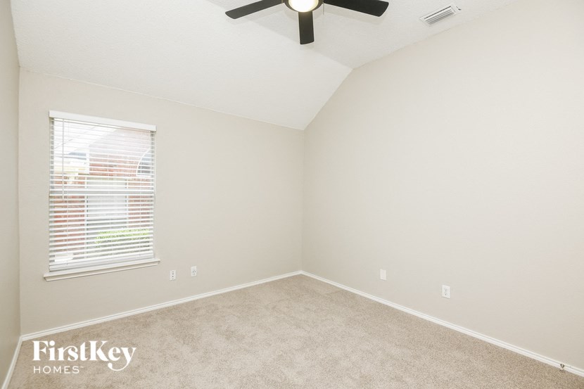 an empty bedroom with a ceiling fan and a window