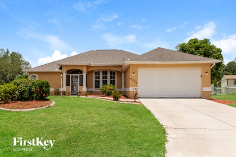 a beige house with a garage and a lawn
