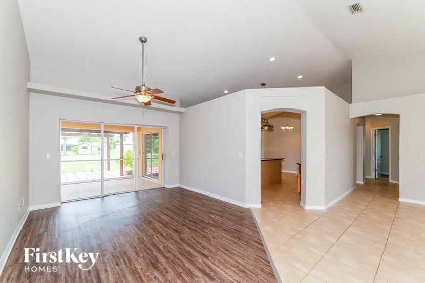 an empty living room and dining room with a ceiling fan