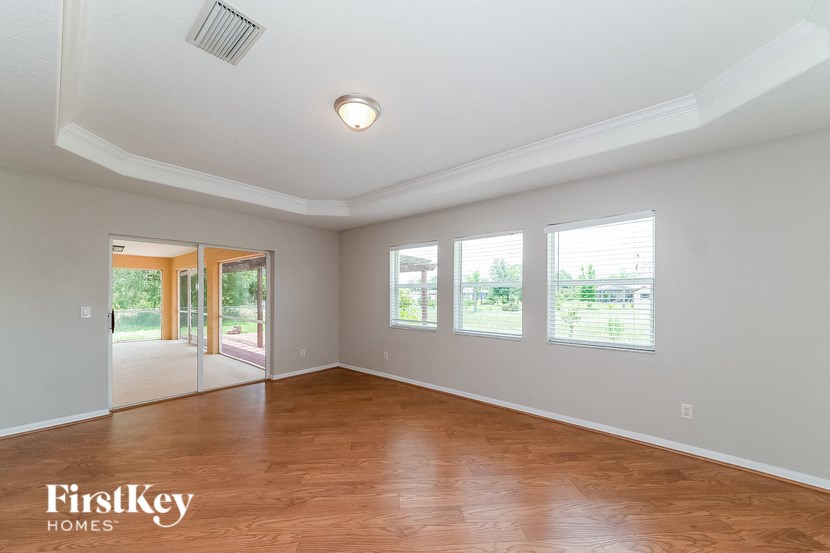 an empty living room with wood flooring and four windows