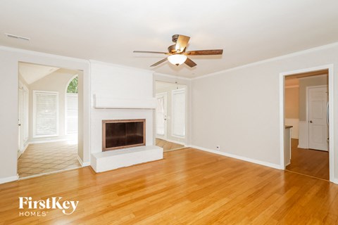 an empty living room with a fireplace and a ceiling fan
