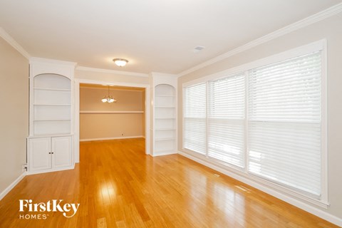 an empty living room with a large window and wood floors