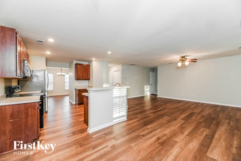 an open kitchen and living room with wood flooring and a ceiling fan