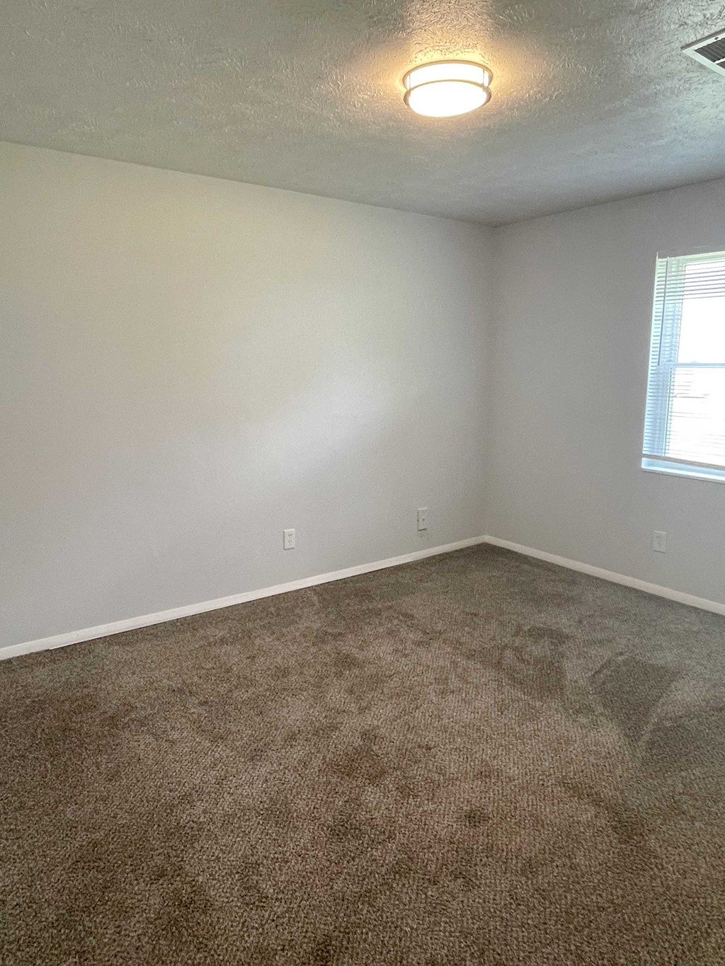 an empty room with carpet and a window