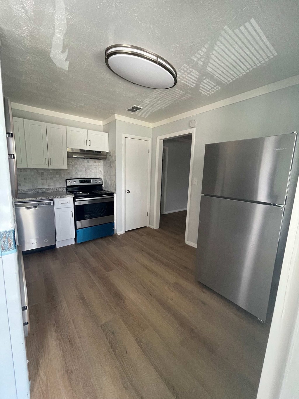 a renovated kitchen with stainless steel appliances and white cabinets