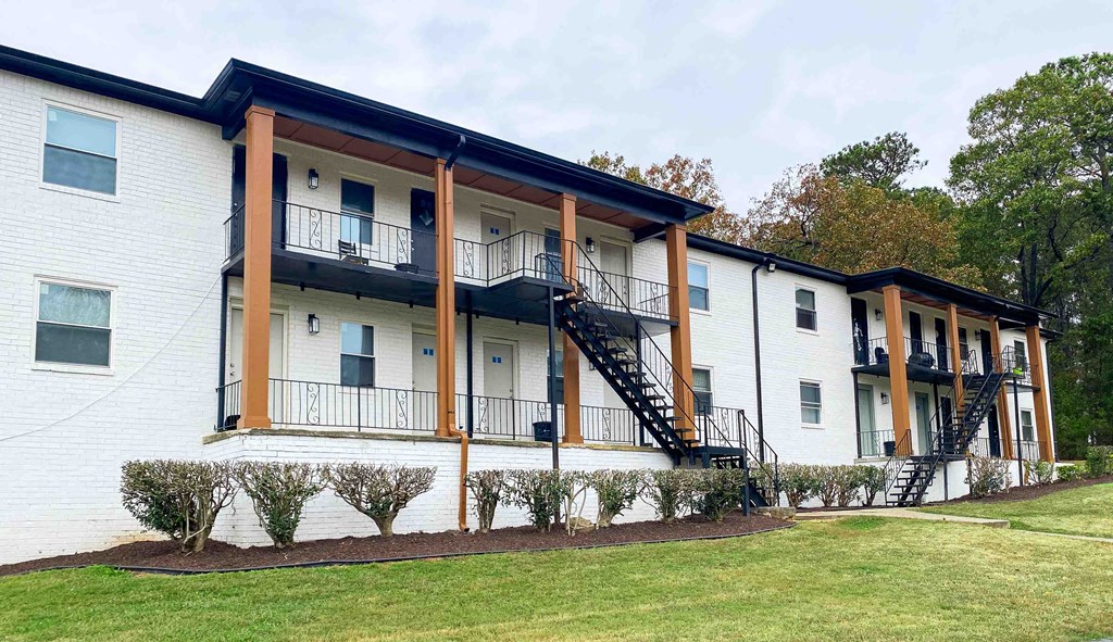 the exterior of an apartment building with a lawn and a staircase