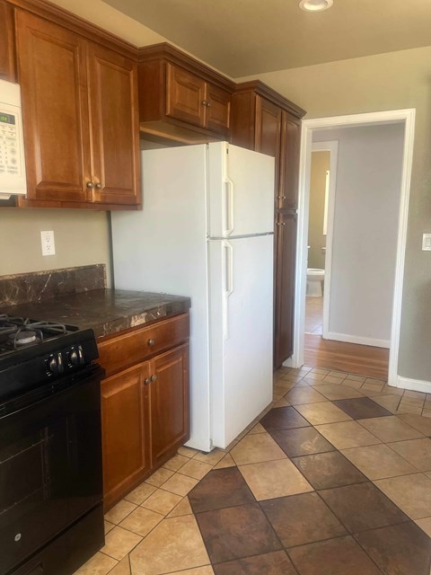 A kitchen with a black stove and white refrigerator.