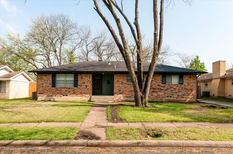 a brick house with a tree in front of it