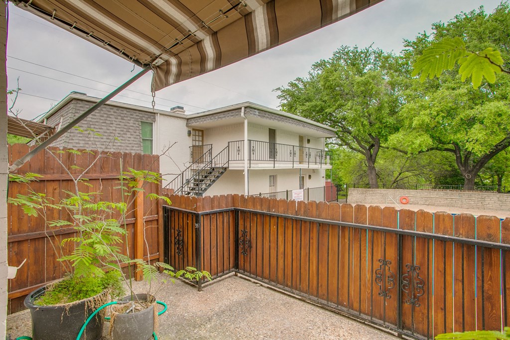 a backyard with a wooden fence and a house behind it