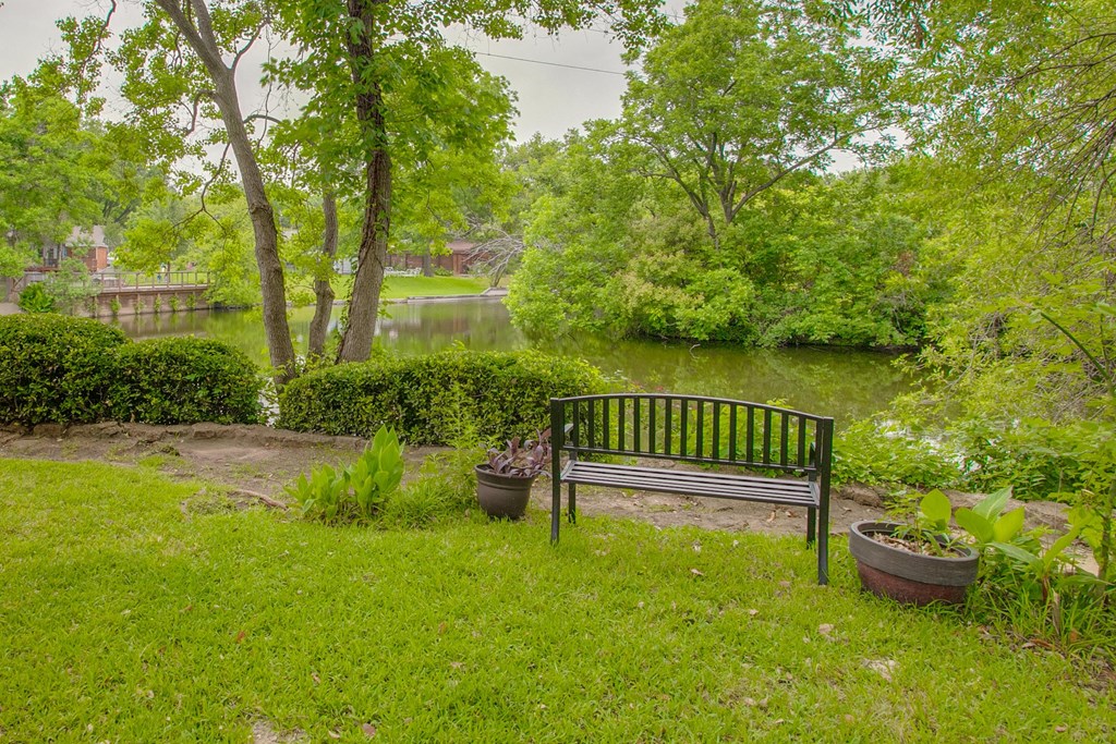 a park bench sitting in the grass near a lake
