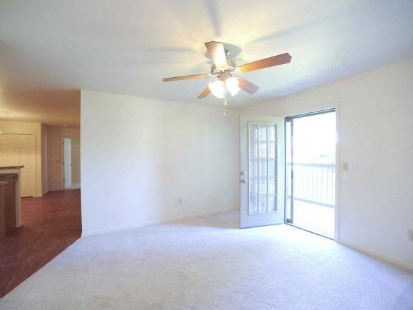 an empty living room with a ceiling fan and a door