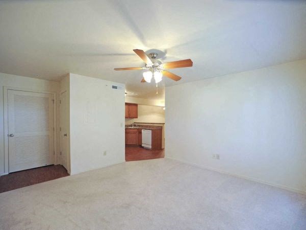 an empty living room with a ceiling fan
