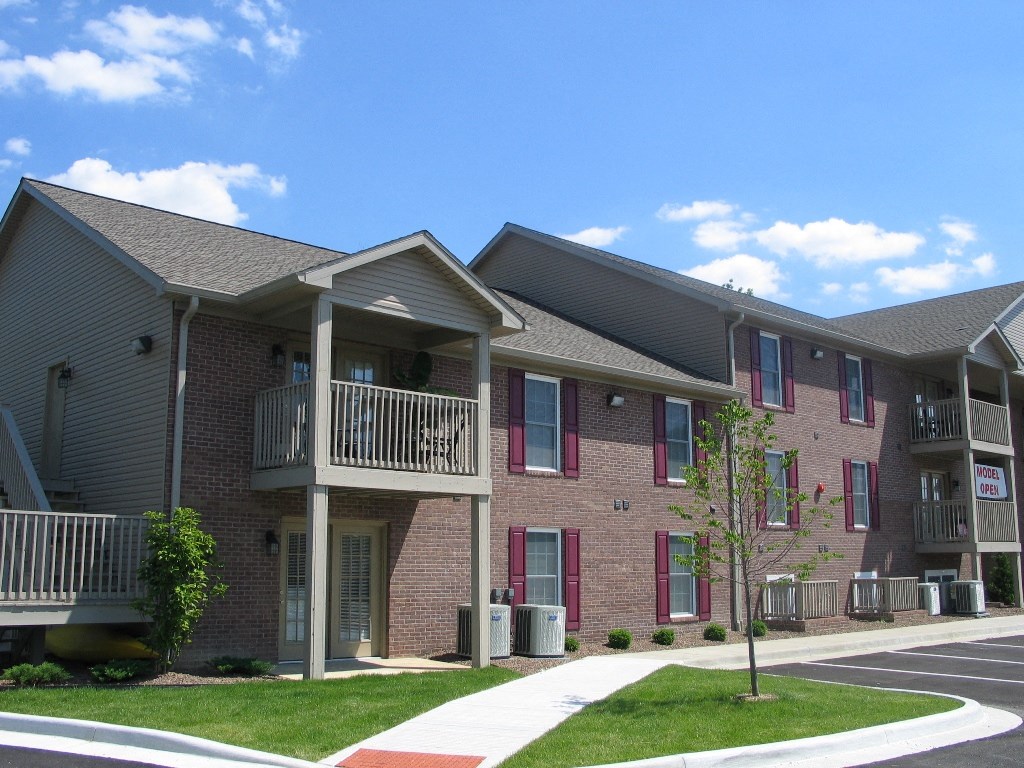 a brick apartment building with a balcony and a sidewalk