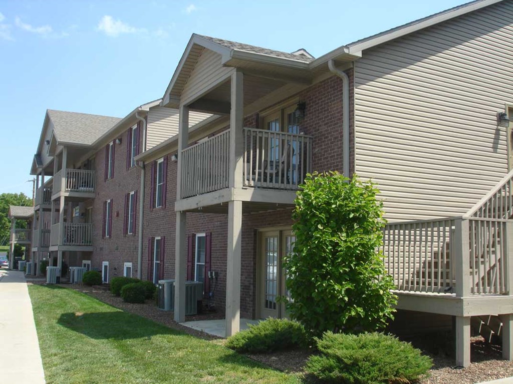 a building with a balcony and a tree in front of it