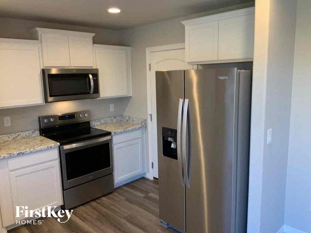 A kitchen with a stainless steel refrigerator, microwave, and oven.