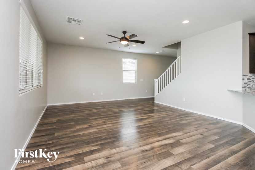the spacious living room with wood flooring and a ceiling fan