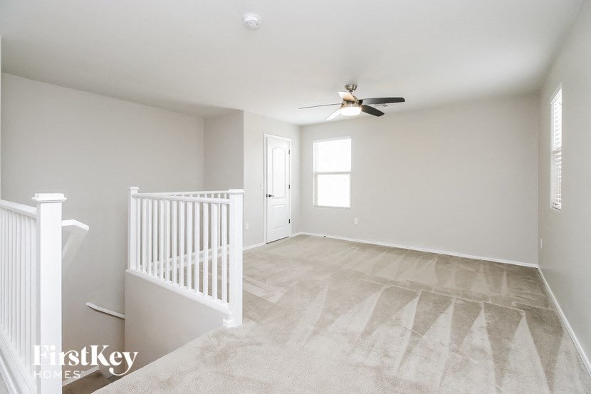a clean and empty living room with a ceiling fan