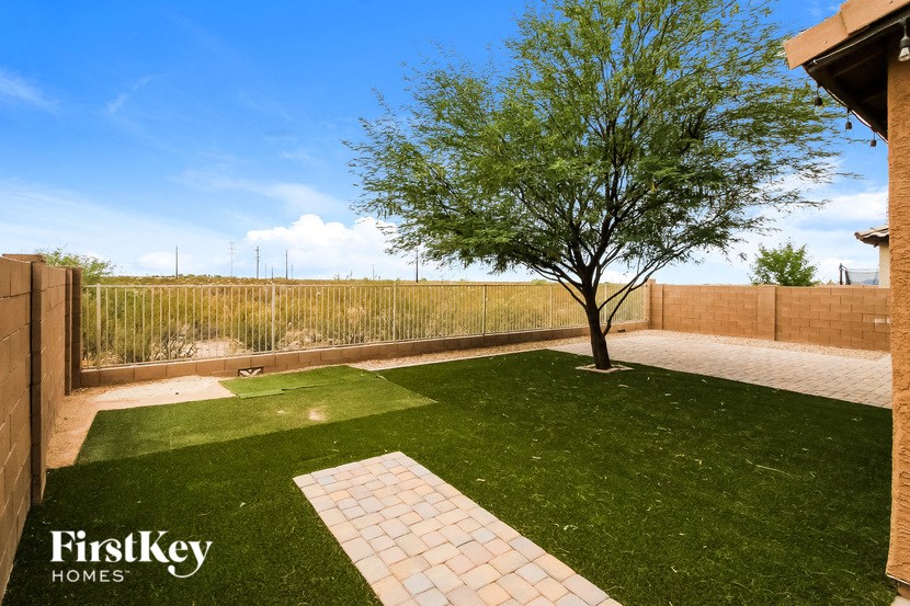 a backyard with artificial grass and a tree