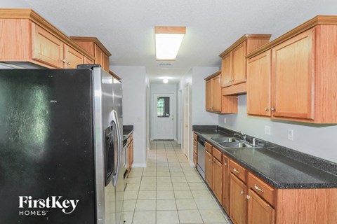 a kitchen with wood cabinets and black counter tops and a refrigerator