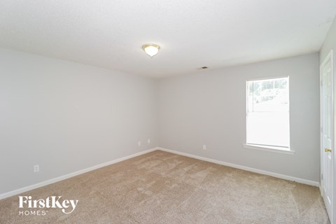 the spacious living room with carpeting and a window